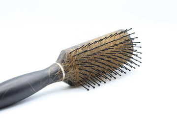 Black plastic hairbrush with blond hair. White background.