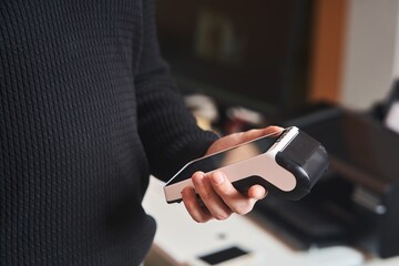 Bank terminal for contactless payment. Acquiring. Young man holds a terminal in his hands.