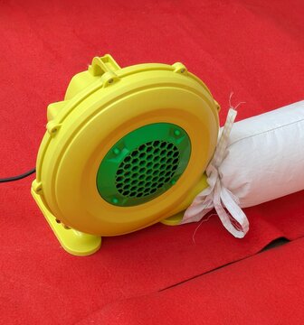 Bomba de aire. Soplador industrial con ventilador centr&iacute;fugo para inflar objetos hinchables, conectado a un tubo de pl&aacute;stico 
