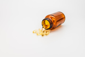 Amber Bottle with Gel Capsules Spilled on a White Background