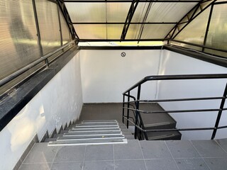 Fototapeta premium Beautiful Staircase in a Modern Interior Space Featuring a Stunning Glass Roof Design. A sleek and elegant staircase gracefully leads downwards in a bright, modern interior featuring a glass ceili