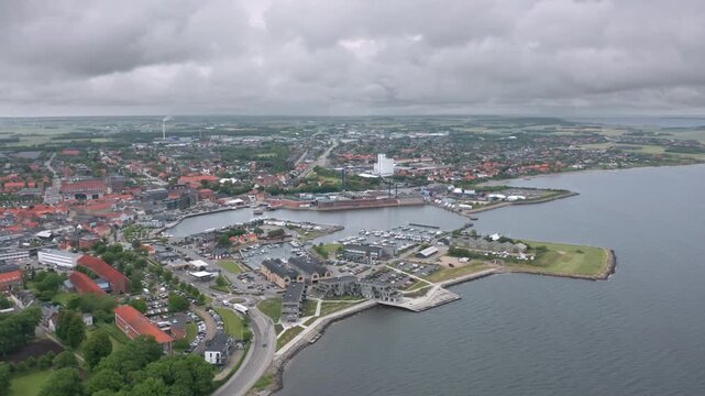 Daytime aerial panorama of Thisted, Denmark &mdash; Skyline view of historic houses, white church, marina, and dramatic sky over the Limfjord waterfront in North Jutland