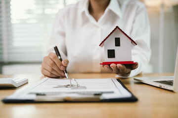 A real estate agent hands over keys after signing a property contract, symbolizing investment,...