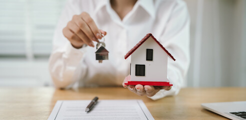 A real estate agent hands over keys after signing a property contract, symbolizing investment,...