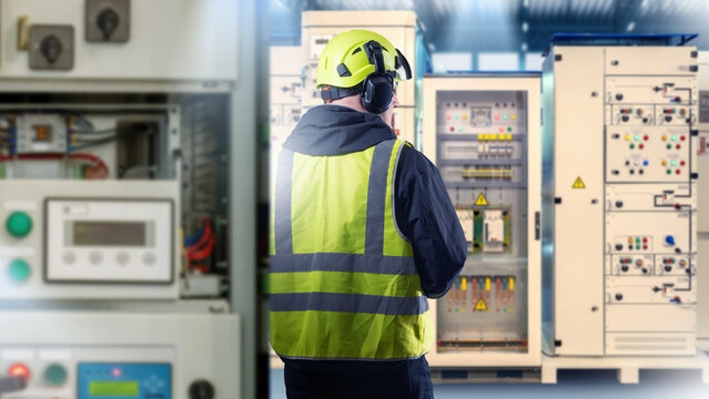 Electrical engineering, technician in safety gear inspecting control panels at power distribution room, electricity, maintenance, energy industry