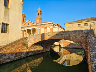 San Pietro church and brick arch bridge over a canal in Comacchio, Emilia-Romagna, Italy, with...