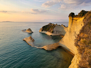 Golden sunset on Cape Drastis cliffs and sea stacks in Corfu