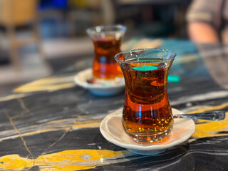 Glass of turkish tea on a porcelain saucer placed on a wooden table. Beverage, tradition,...
