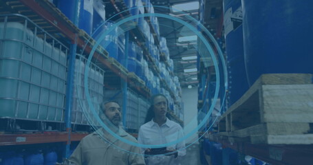 Walking workers in uniform inspecting drums and IBCs in aisle, with tablet and racks
