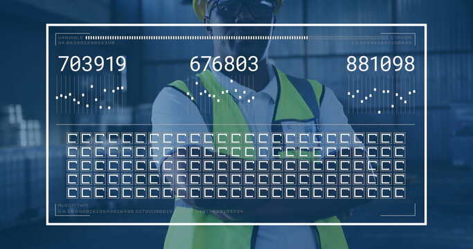 Standing site supervisor crossing arms inside warehouse wearing yellow hat, vest, with data overlay - Powered by Adobe