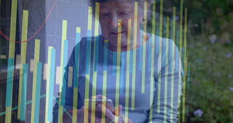 Analyzing senior woman holding smartphone and studying data on home patio, with bar and line graphs