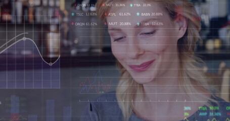 Reviewing professional wearing gray top analyzing market data in cafe, with line graphs, bar charts