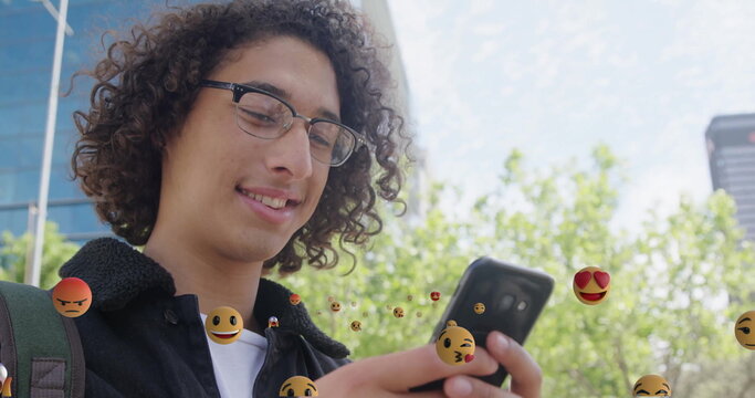 Checking student with jacket and backpack scrolling smartphone at park, floating emojis, copy space