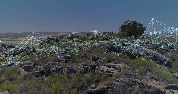 Fototapeta Overlaying glowing network spanning rocky hillside under clear blue sky, overlooking farmland