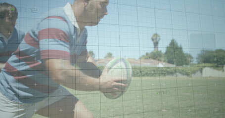 Charging rugby player in striped jersey gripping rugby ball and driving forward on suburban field