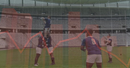 Rugby players wearing navy jerseys lifting teammate catching white rugby ball in lineout in stadium