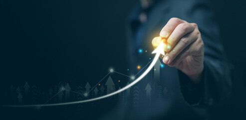 Businessman hand drawing glowing upward arrow on virtual screen symbolizing business market growth,...