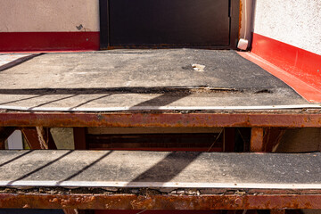 Warped and lifted porch surface with exposed reinforcement, indicating imminent structural failure from environmental stress