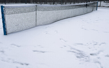 Row of snow covered tennis court nets, in a weather delay concept, with space for text