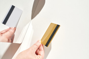 Hands holding credit card and mirror reflection on white background.
