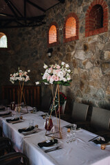 Photo of design, decor, table decorated with flowers and dishes for guests at a wedding celebration.
