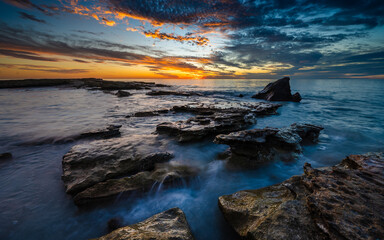 Sunset view of Cable Beach Broome with rocky formations and silky water at high tide