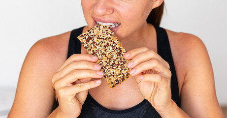 Close-up photo woman eating seeded cracker.