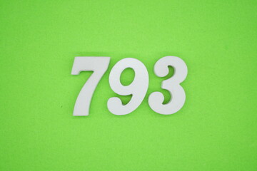 The numbers are made of white painted wood and placed on a green paper background.