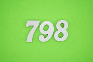 The numbers are made of white painted wood and placed on a green paper background.