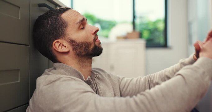 Man, headache and stress with anxiety, depression or burnout on kitchen floor in home. Upset, disappointed or tired and frustrated person with migraine, fatigue or pain in trouble or issue in house