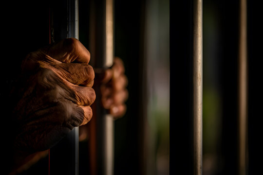Closeup of hands gripping prison bars, symbolizing confinement, struggle, and the desire for freedom