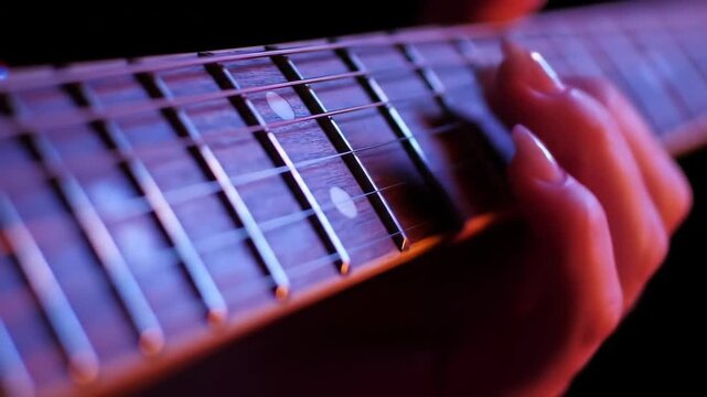 Close-up of a hand playing strings on a fretboard guitar