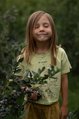 a girl ate a blueberry, closed her eyes and enjoyed the taste. Dressed in a yellow T-shirt, shorts