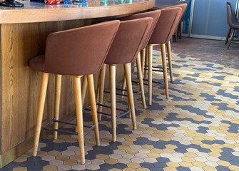 Bar counter with stools and hexagonal floor tiles. Hospitality, leisure, and social culture in...