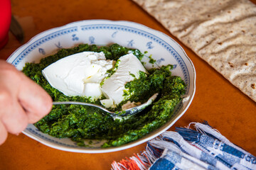 “Preparation of homemade spinach pie with filo pastry sheets, showing fresh spinach filling being...