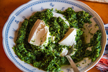“Preparation of homemade spinach pie with filo pastry sheets, showing fresh spinach filling being...