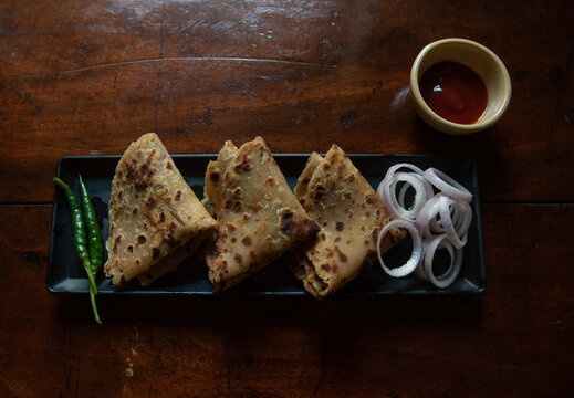 Aloo paratha served in a tray along with condiments. Top view, selective focus.