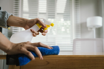 A woman is cleaning the house, cleaning the furniture with a spray and a duster, emphasizing hygiene, order, and responsibility towards the home.
