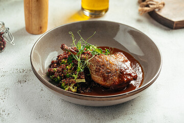 Juicy grilled duck leg served with quinoa and broccoli in sauce