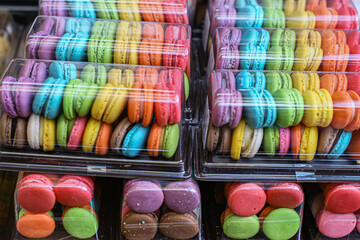 Colorful rainbow macarons neatly arranged in a clear box. Sweet French-inspired dessert popular in...