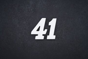 The numbers are made of white painted wood and placed on a black plastic background.