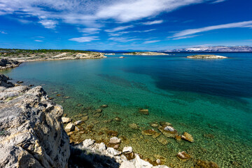 Azure water in the Adriatic Sea, rocky coast of the island of Rab, cloudy, threatening sky,