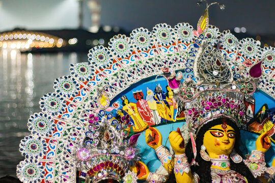 Durga Puja visarjan on vijaya dashami or dussehra with idol of goddess Durga being immersed in river Hooghly of kolkata. City lights reflecting on river water in background