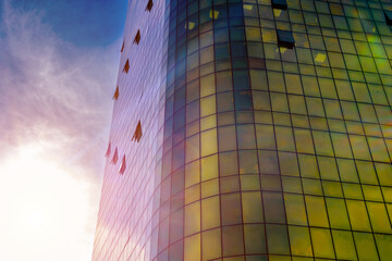 Modern glass skyscraper against blue sky in urban setting