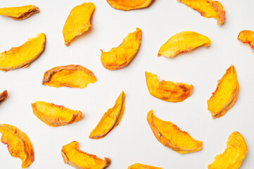 Dried peach slices scattered on light background, pattern. Organic tasty sweet dried fruit, healthy...
