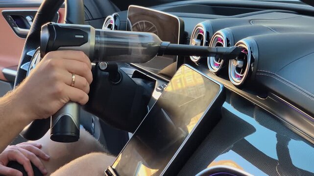 The driver cleans the car's deflectors using a cordless vacuum cleaner