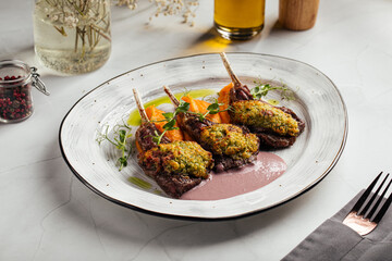 Three baked lamb chops with herb crust, served with vegetables and sauce