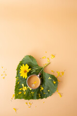Vertical coffee with flower petal served on leaf in heart shape, styled with sunflower and petals.