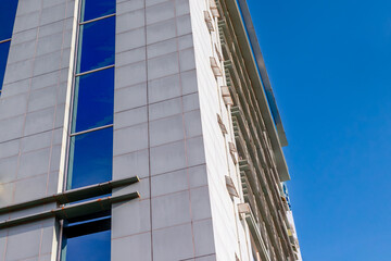 Obraz premium Modern high-rise building with glass windows against clear blue sky