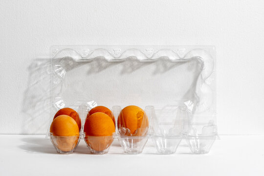 Five brown eggs in clear plastic carton on white surface under bright light